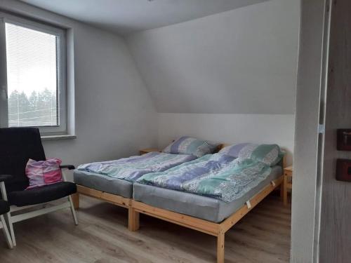 een slaapkamer met een bed, een stoel en een raam bij Objevte krásu Beskyd , navštivte chatu Lojza in Staré Hamry
