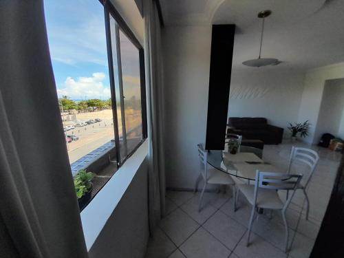 a living room with a table and chairs and a window at dúplex beira-mar in Maceió