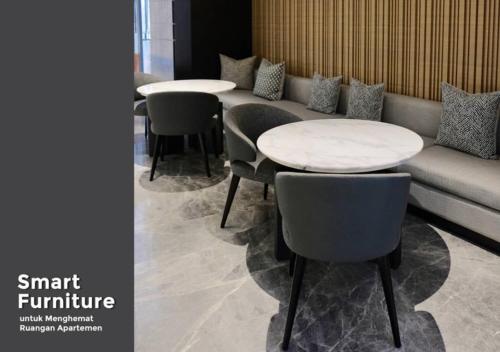 a living room with two tables and a couch and chairs at Tentrem Room at Springwood Residence in Warungmangga