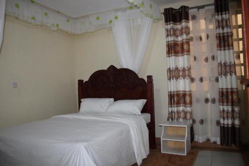 um quarto com uma cama com lençóis brancos e cortinas em Furnished Apartments in Nairobi 14km from Jomo Kenyatta International Airport and SGR em Embakasi