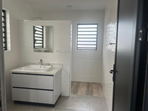 Baño blanco con lavabo y espejo en Lagun Sunset Resort All Natural Clothing Optional, en Lagun