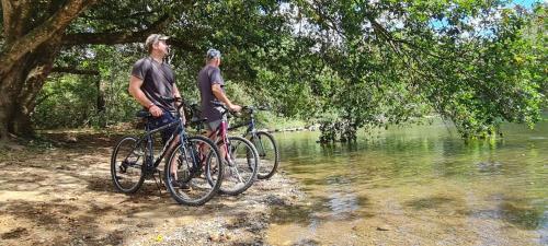 two men standing with their bikes next to a river at La Qhia Eco Retreat in Santa Fe