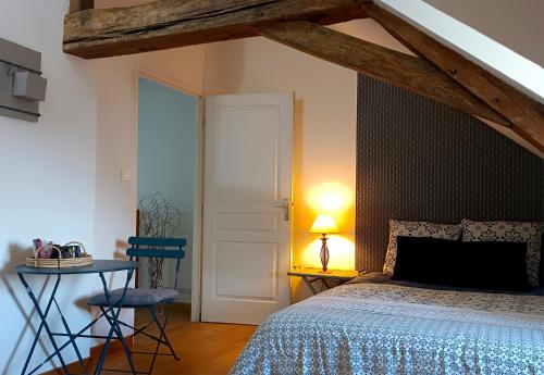 1 dormitorio con 1 cama y 1 mesa con lámpara en B&B Côté Loire, en Les Rosiers