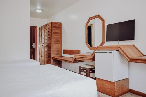 um quarto com uma cama e uma televisão de ecrã plano em Poty Praia Hotel em Porto Seguro
