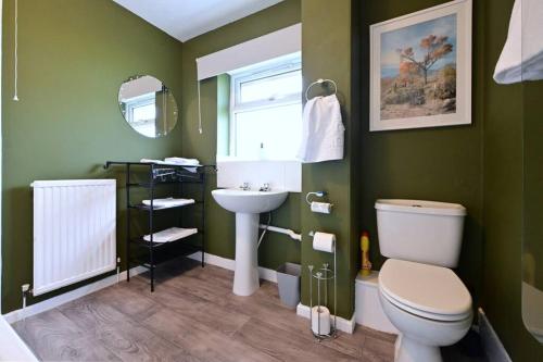 a green bathroom with a toilet and a sink at Reduced rates for weekly, monthly and longer stays in Durham