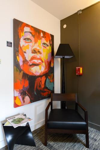 a painting of a woman on a wall next to a chair at Hype Hôtel in Biscarrosse