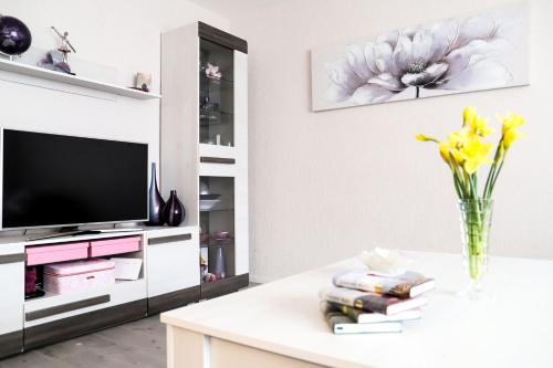 una sala de estar con TV y un jarrón de flores amarillas en Magnolia apartment en Liepāja
