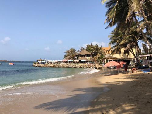 una playa con un grupo de sombrillas y el océano en Magnifique Appartement avec PISCINE, 3 Chambres, 4 Salles de Bain, Salle de Gym et Terrasse, LUXE ET COMFORT aux ALMADIES, en Dakar