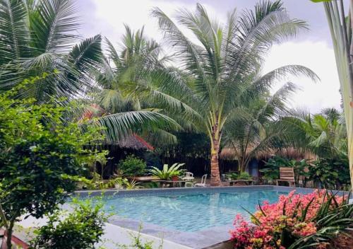 a swimming pool in a garden with palm trees at Bohol Island Homestay in Dauis