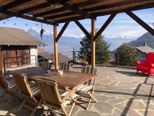 a wooden table and chairs on a patio with mountains at Chambre sur terrasse in Nendaz