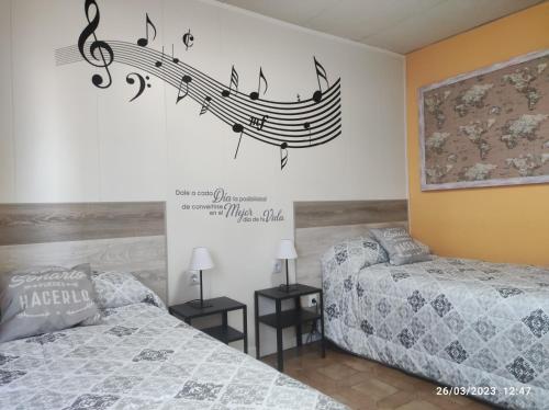 1 dormitorio con 2 camas y notas musicales en la pared en Acogedor, en Zaragoza