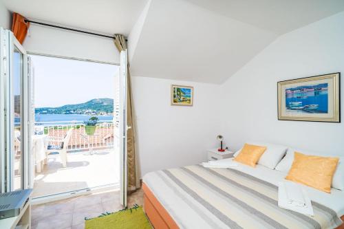 a bedroom with a bed and a balcony at Apartments Villa Cerjak in Slano