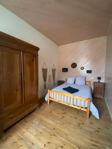 1 dormitorio con 1 cama y armario de madera en Maison de casteljaloux 9 personnes en Casteljaloux