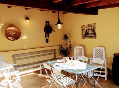 a dining room with a table and white chairs at B&B Su Frori Arrubiu in Teulada