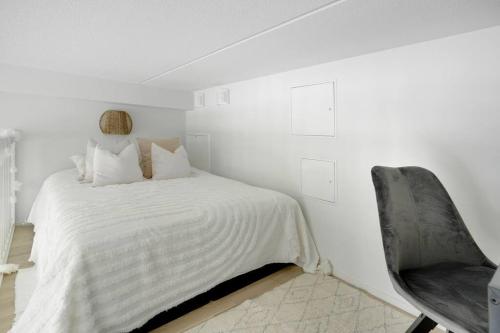 um quarto branco com uma cama e uma cadeira em Maple Loft Apartment 