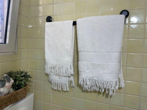 twee witte handdoeken hangend aan een rek in een badkamer bij לופט משגע במיקום מרכזי ברמת גן in Ramat Gan