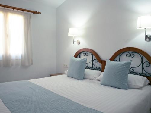 een slaapkamer met een bed met twee blauwe kussens bij Bungalows Los Almendros - Exclusive Vacation Club in Playa del Inglés