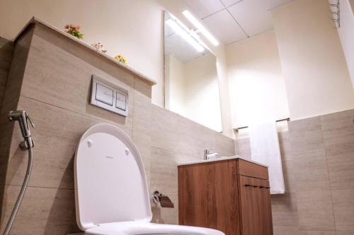 a bathroom with a toilet and a sink and a mirror at Masdar Mirage Oasis 2BR Duplex with Pool Access in Al Qurayyah
