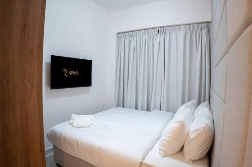 1 dormitorio con 1 cama con sábanas y almohadas blancas en Masdar Mirage Oasis 2BR Duplex with Pool Access en Al Qurayyah
