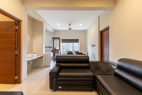 a living room with a black leather couch and chairs at Amminis Mansion by Doris Homes in Trichūr