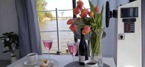 a table with two wine glasses and a vase of flowers at ARKA 1 domki na wodzie w Mielnie, rower wodny, bezpłatny WIFI, Parking in Mielno