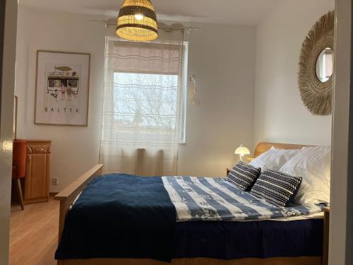 ein Schlafzimmer mit einem Bett mit einer blauen Decke und einem Fenster in der Unterkunft Apartament Dziwnów in Dziwnów