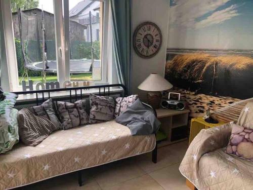 a living room with a couch and a clock on the wall at Apartament Heniokite in Rewa
