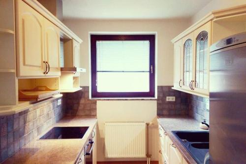 uma cozinha com armários brancos e uma janela em Farmhouse Apartment Happy Cow em Mavčiče