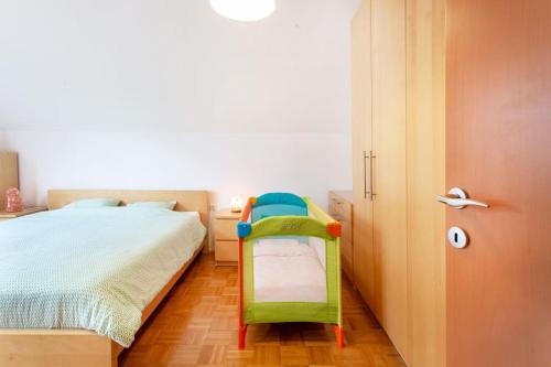 ein Schlafzimmer mit einem grünen Stuhl neben einem Bett in der Unterkunft Farmhouse Apartment Happy Cow in Mavčiče