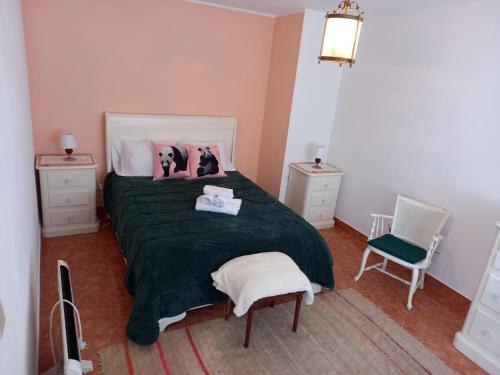 a bedroom with a bed with a green blanket and two chairs at Casa da Ribeira em Rabal in Rabal