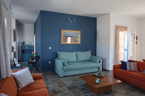 a living room with a couch and a blue wall at Psamathe Aegina Apartments in Egina