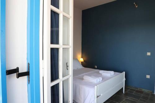 a bedroom with a bed with a blue wall at Psamathe Aegina Apartments in Aegina Town