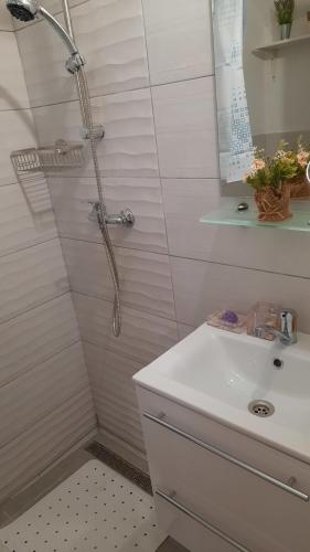 une salle de bain blanche avec une douche et un lavabo dans l'établissement Apartma Seaya, à Izola