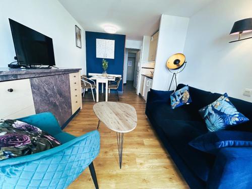 ein Wohnzimmer mit einem blauen Sofa und einem Tisch in der Unterkunft Gabrielle Appartements CANNES in Cannes