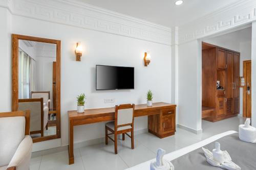 a living room with a desk and a television at HOTEL WHITE HOUSE, Munnar in Munnar