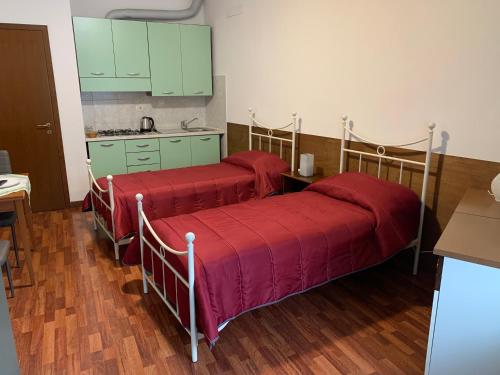 two beds in a room with green cabinets and a kitchen at All’angolo in Sale