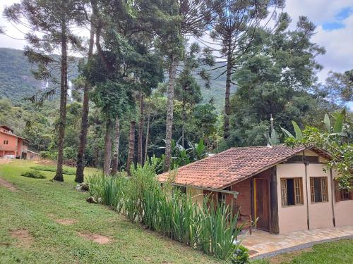 a small house in a field next to a forest at Casa Cacau Boutique B&B - Sítio Salamandra Vale do Matutu in Aiuruoca