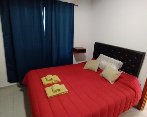 a bedroom with a red bed with two towels on it at Cabaña los Hielos in El Calafate