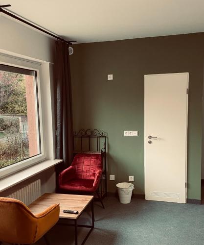 a living room with a red chair and a window at Pension Christine in Neu-Anspach