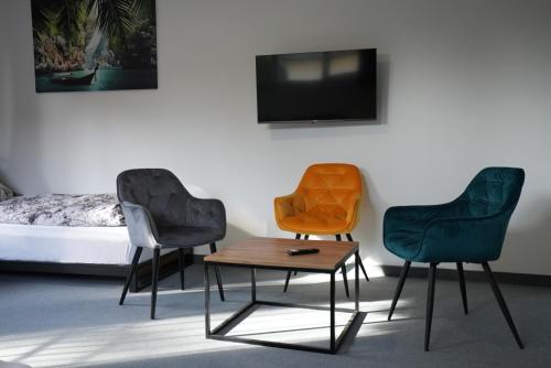 three chairs and a table in a room with a tv at Pension Christine in Neu-Anspach