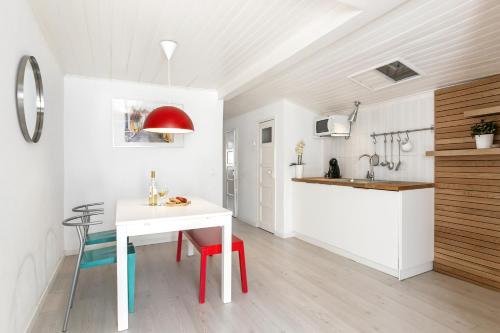 a white kitchen with a white table and red chairs at Ana's House in Óbidos