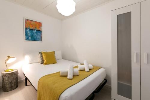 a white bedroom with a bed with a yellow blanket at Ana's House in Óbidos