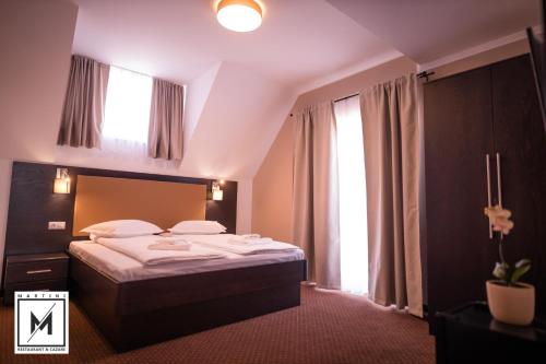 um quarto com uma cama e uma grande janela em Martini Restaurant & Cazare em Sebeşel