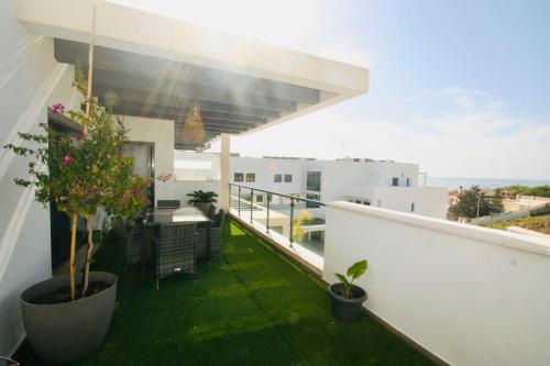 Atico con piscina, golf, vistas al mar في توري دي بيناغالبون: شرفة مع العشب الأخضر والنباتات على المبنى