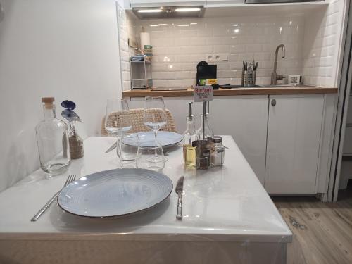 - un comptoir blanc avec 2 assiettes et des verres à vin dans l'établissement Studio les jardins de la brèche, à Hermanville-sur-Mer