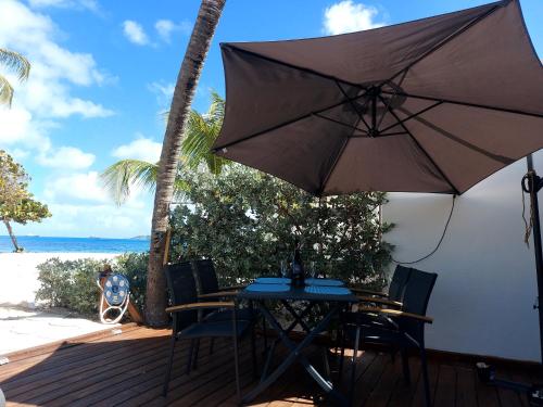 a table and chairs with an umbrella on the beach at Tekila Beach, appt-condo au bord de mer a Saint-Martin SXM in Baie Nettle