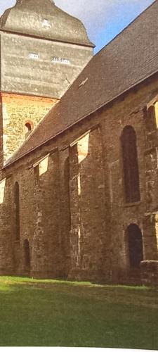 an old brick building with a tower in the background at Pine Crest Ferienwohnung in Harzgerode