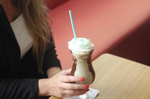 a woman is holding a milkshake with whipped cream at ibis Sao Jose dos Campos Dutra in São José dos Campos