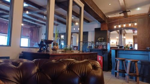 a living room with a leather couch and a bar at The Renishaw Rooms in Renishaw
