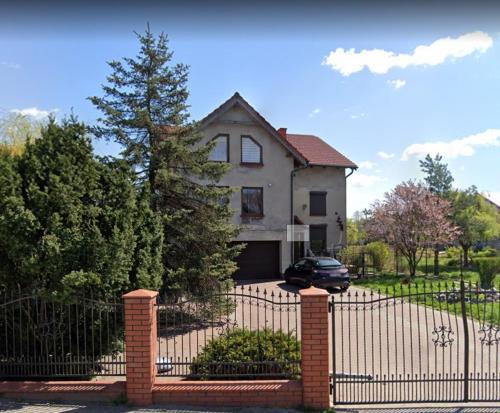 une maison blanche avec une clôture et une voiture dans l'établissement Magnollia, à Grębocin